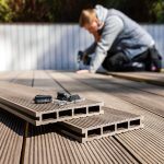 wpc terrace construction - worker installing wood plastic composite decking boards